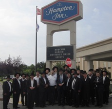 Participants stand outside a Hampton Inn in Pennsylvania  during a tour of nearby OU certified companies.  The sign reads “Bruchim Haboim [Welcome] Orthodox Union Guests.” 