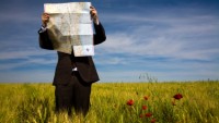 businessman lost in field using a map