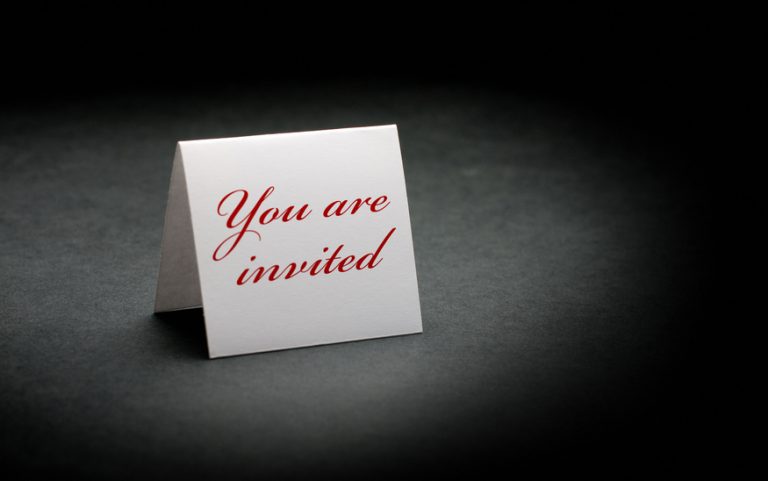 you are invited written in red on a white sign. image is over a black paper background