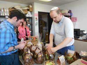 (L-R) Brandon Levine and Moishe Hammer prepare Yachad gift baskets for Rosh HaShana as Ava Lang Soffer, creative director and production manager, looks on. (Bayla Sheva Brenner)