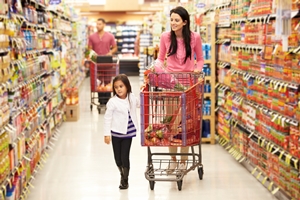 Mother And Daughter Walking Down Grocery Aisle In Supermarket