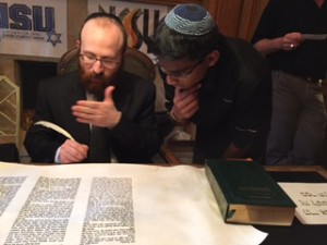An NCSYer looks on as the scribe writes a letter in Midwest NCSY's new Sefer Torah. 